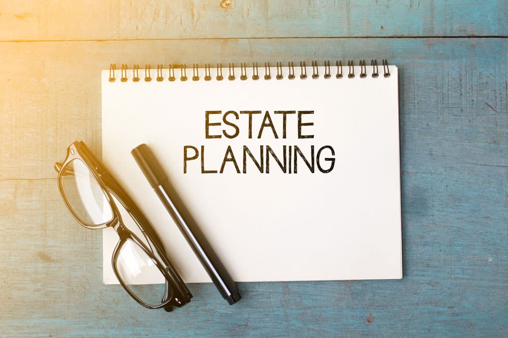 Estate Planning written on notebook with glasses and pen next to it